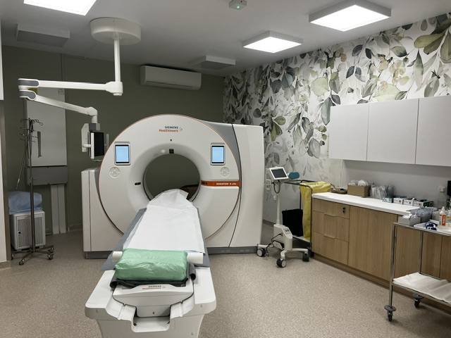 The scanner, the patient table, the ceiling-mounted light arm and the fitted furniture.