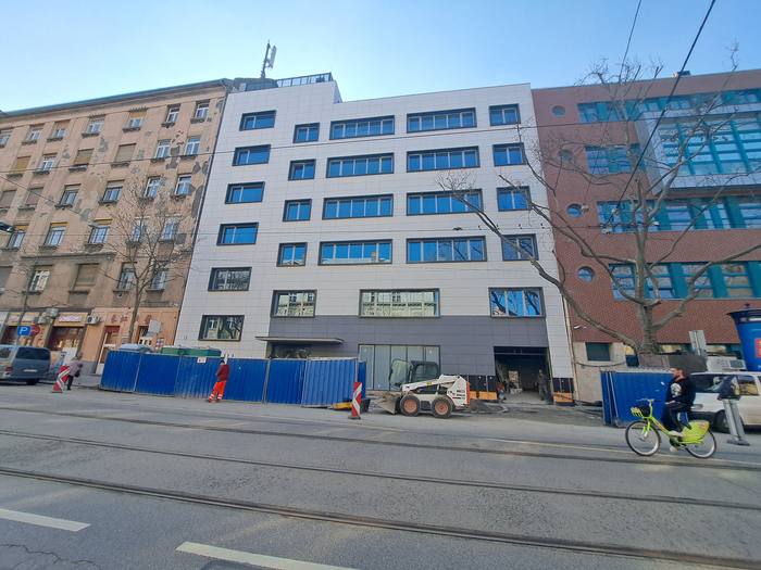 Az utcai homlokzat a kivitelezés idején, építési kerítéssel.
